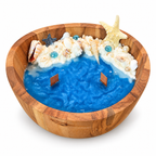 Ocean Bowl Candle in a round wood bowl with blue wax, white foam and seashells